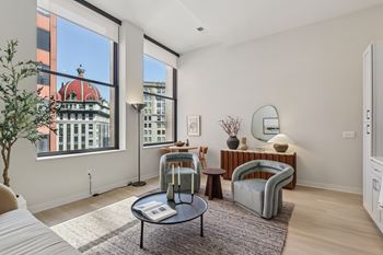 A living room with a large window and a view of a building with a red roof.